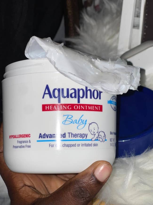 reviewer holding a instrumentality of Aquaphor Healing Ointment Baby Advanced Therapy