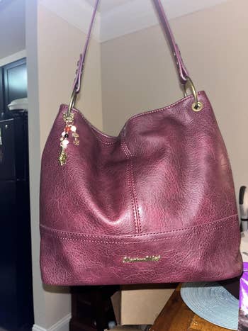 A textured handbag with gold hardware and a charm, ideal for shopping or casual outings