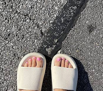 reviewer wearing the beige sandals outside