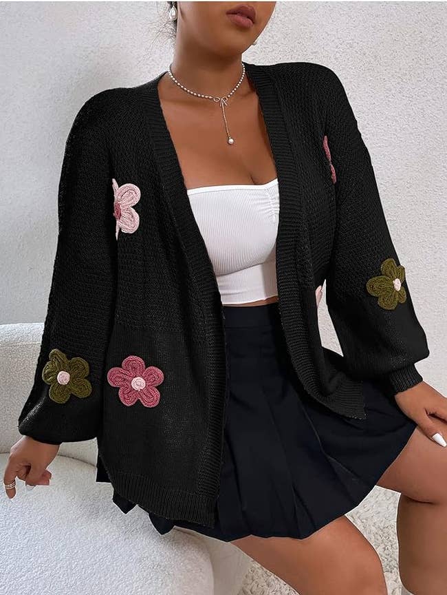 model in black cardigan with knit floral design and a matching black skirt