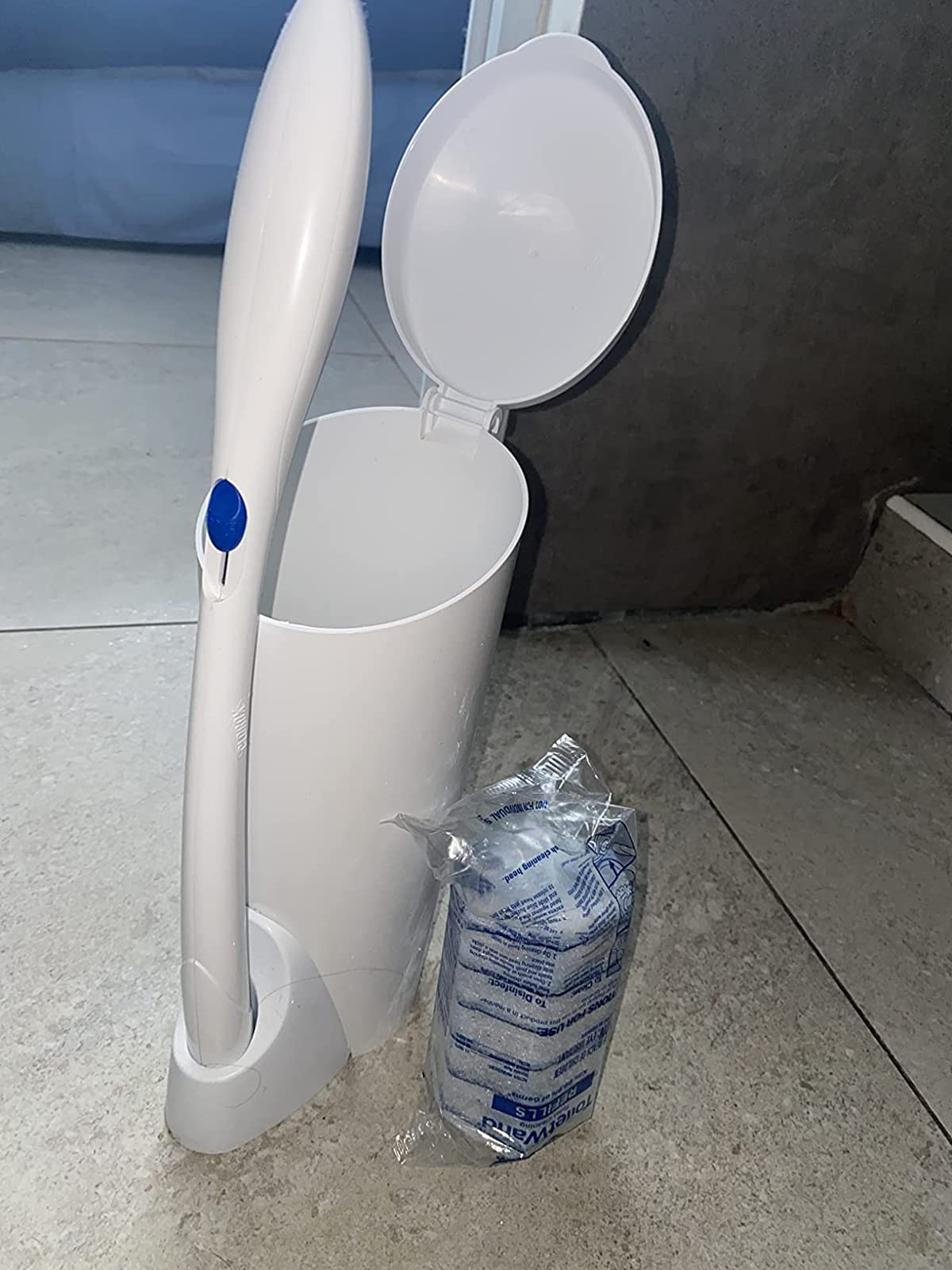 reviewer photograph  of the achromatic  toilet wand and holder adjacent  to a battalion  of disposable sponges