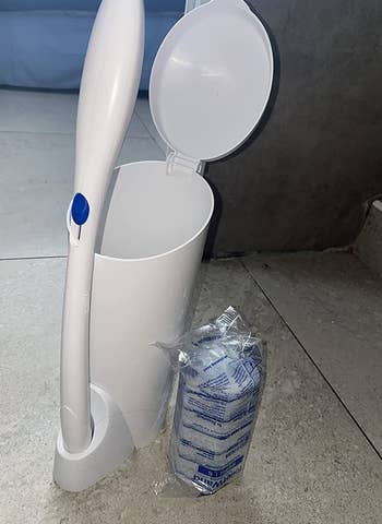 reviewer photo of the white toilet wand and holder next to a pack of disposable sponges