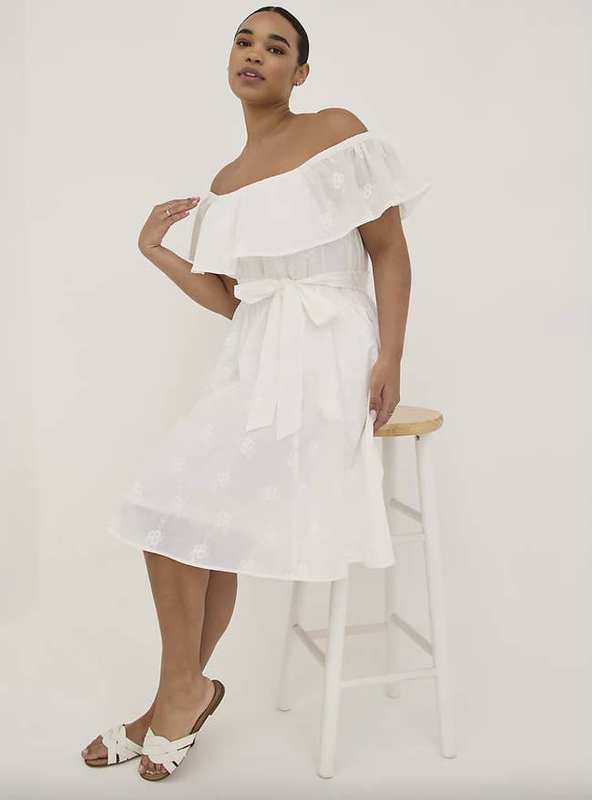 a plus size model wearing the white off-the-shoulder dress