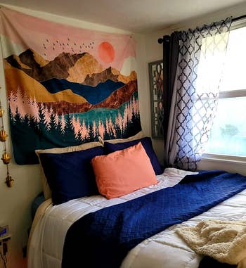 reviewer photo of the tapestry hanging above their bed