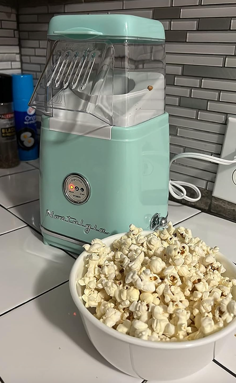 a small blue electric popcorn maker with a clear top where the popped corn comes out 