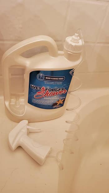 reviewer photo of the bottle of shower cleaner on the ledge of a tub