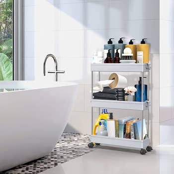 The 3  tiered cart adjacent  to a bathtub