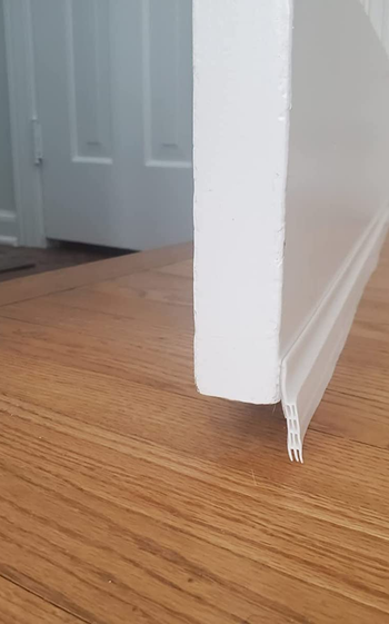 a side shot of the draft stopper applied on a front door, blocking the gap underneath