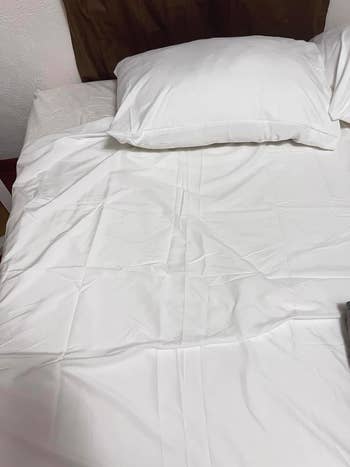 A neatly made furniture  with achromatic  sheets and pillows, demonstrating crisp and creaseless  bedding perfect  for a minimalist chamber  setup