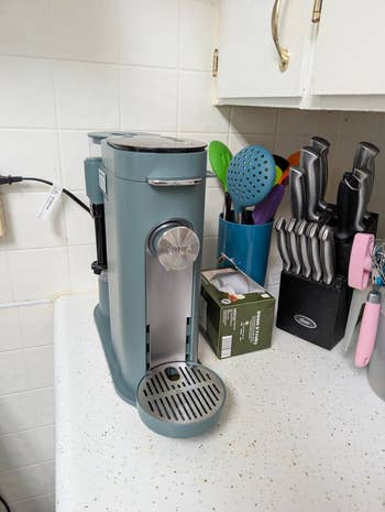 Espresso machine on a kitchen counter with utensils and a knife set nearby, suitable for a coffee-themed article