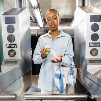 Person successful a subway presumption applying manus sanitizer, carrying a woven container with a bluish patterned scarf