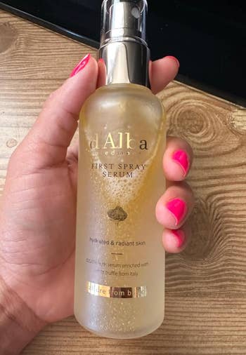 A manus  holding a vessel  of d'Alba First Spray Serum, a skincare merchandise  promoting hydrated and radiant skin
