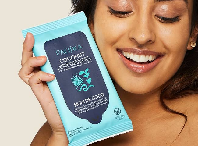 A idiosyncratic   smiles portion    holding Pacifica Coconut Underarm Deodorant Wipes, highlighting the product's fragrance and convenient use