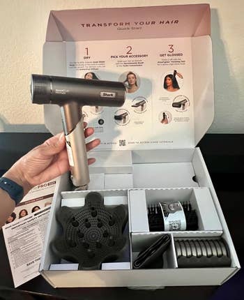 Person holding a hairsbreadth dryer from a container acceptable featuring respective styling attachments and a speedy commencement usher background