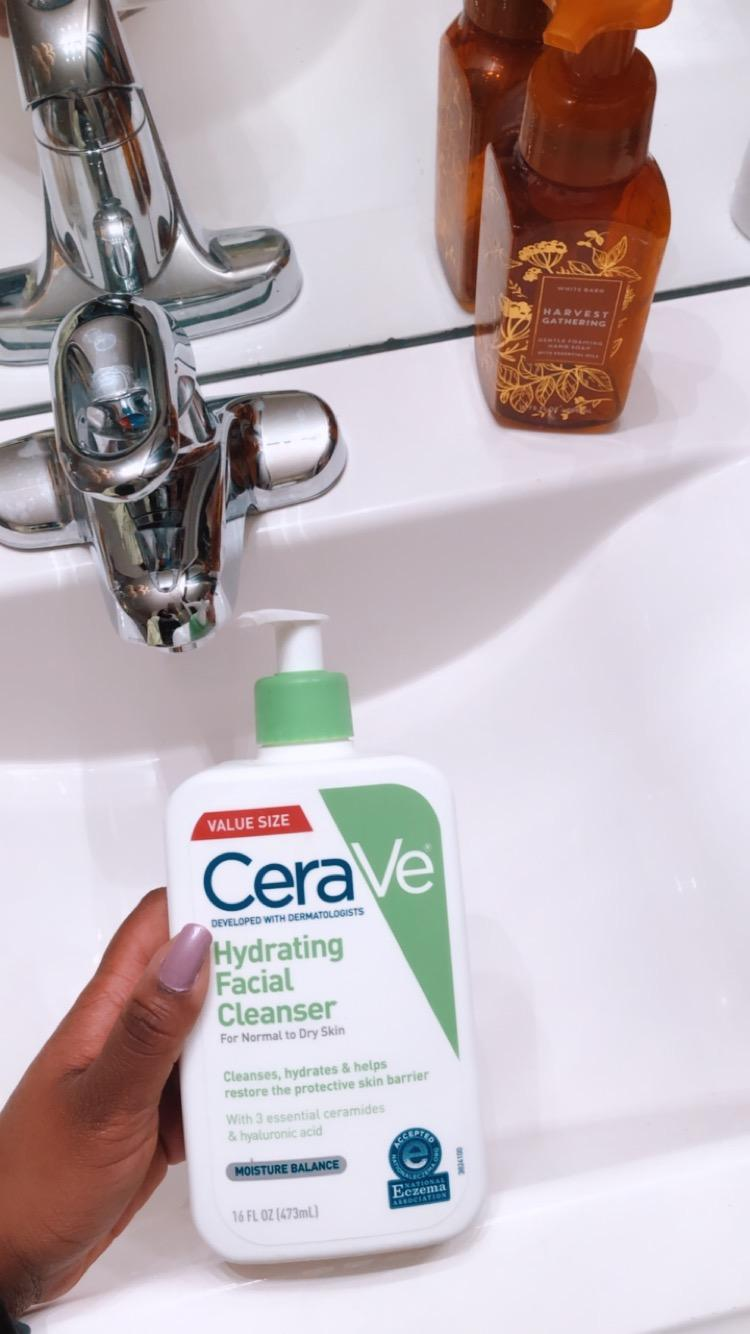 reviewer holding the white and green cleanser bottle