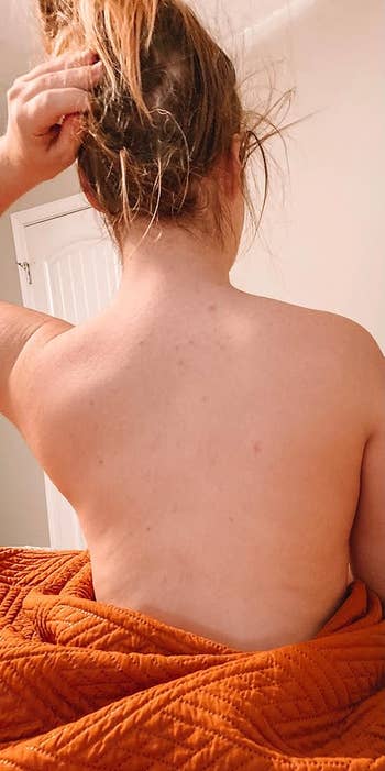 Person sitting with their backmost  to the camera, wrapped successful  a quilt, hairsbreadth  tied up, suggesting a casual, location  setting