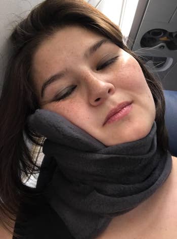 reviewer asleep on a plane using the neck pillow