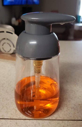 Reviewer image of gray and clear dispenser with orange soap