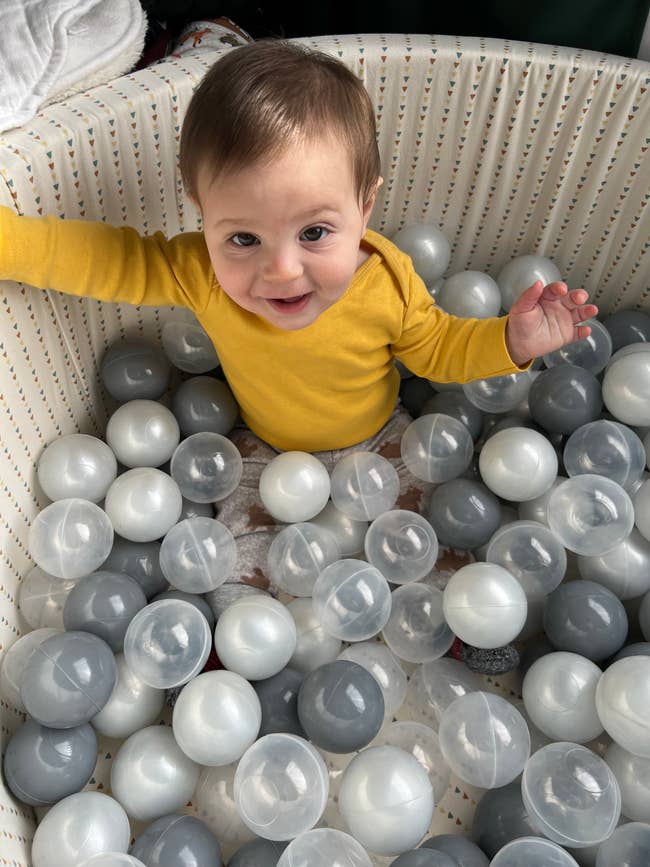 editor's child in a plush ball pit filled with clear, pearl, and gray balls