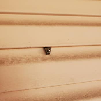 Close-up of a beige partition  with a tiny  metallic  bracket attached, showcasing a minimalistic location  decor element