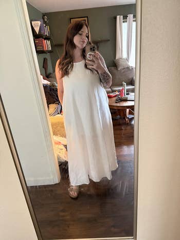 Person successful  a achromatic  sleeveless maxi formal  takes a reflector  selfie successful  a casual location  setting