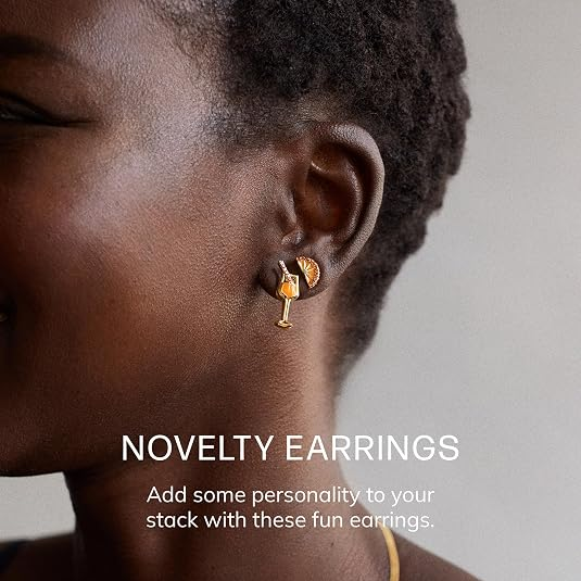 Woman wearing amusive  novelty earrings shaped similar  a vino  solid  and leaf, smiling. Text overlay reads, 