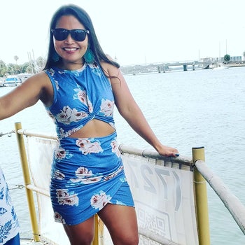 a reviewer wearing the bodycon dress with a front stomach cutout in blue with a white floral print 