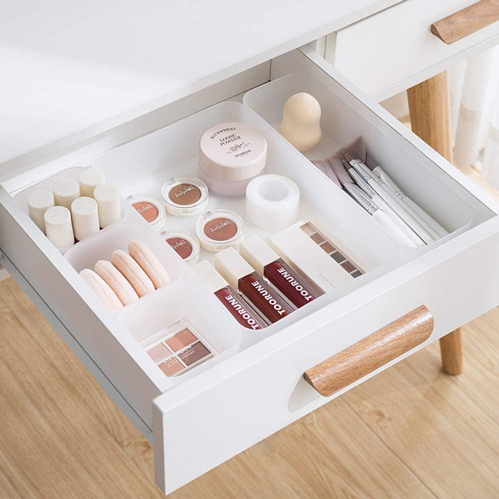 drawer with various size square and rectangular frosted white bins holding beauty products