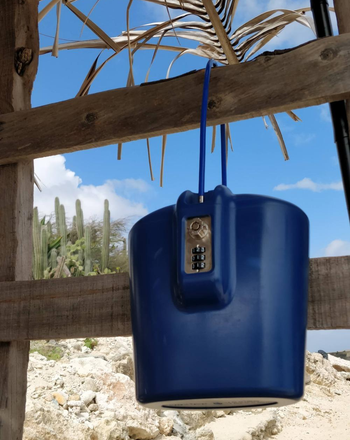 a reviewer photo of a navy safe hanging from a banister on the beach 