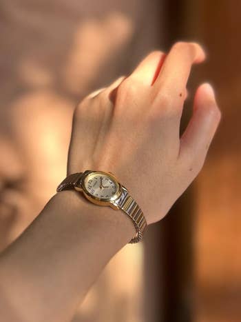 Person's wrist wearing a silver watch with round face.
