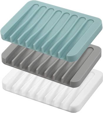 three soap dishes: one teal, one gray, and one white