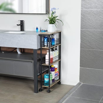 black slim cart stored next to a bathroom sink holding various toiletries