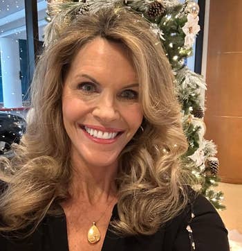 Person smiling successful beforehand of a decorated Christmas tree, wearing a achromatic apical with a golden pendant necklace