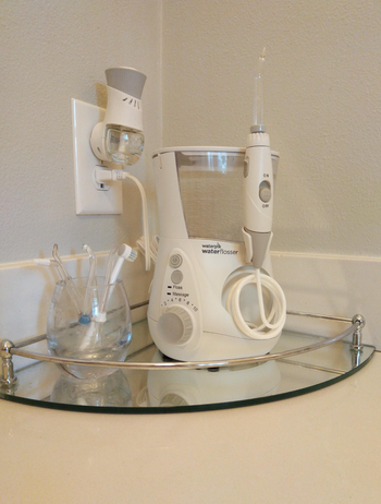 a reviewer showing their water flosser in white on their bathroom countertop