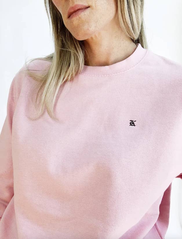 a model in a pink sweatshirt with a K embroidered on it