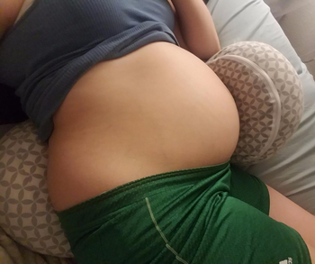 Reviewer laying on the gray and white Boppy pregnancy pillow