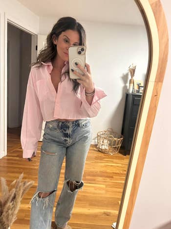 Reviewer in a mirror selfie wearing a pink oversized shirt and distressed jeans