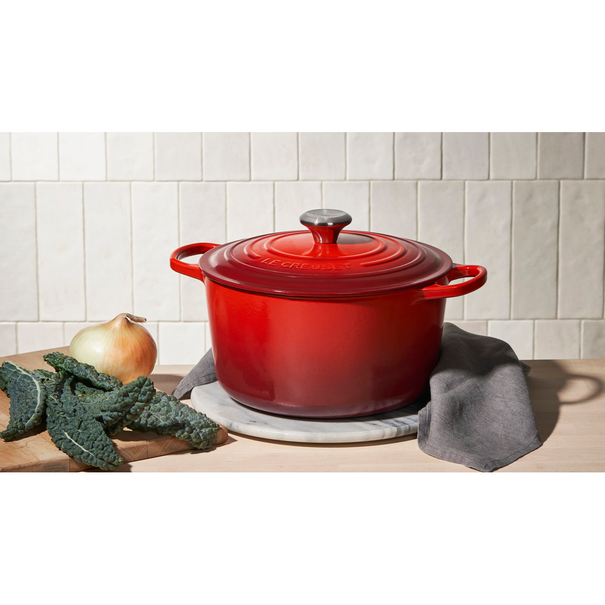 Red formed  robust  Dutch oven connected  a antagonistic  with kale and an bulb  beside it