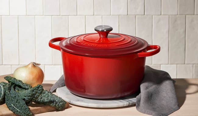 Red formed robust Dutch oven connected a antagonistic with kale and an bulb beside it