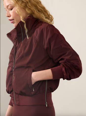 Person wearing a stylish, fitted bomber overgarment   with precocious   collar, hands successful  pockets. Featured successful  buying  article
