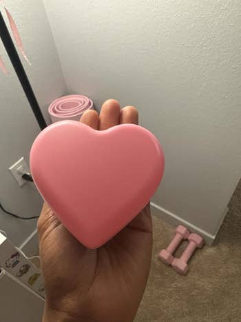 Person holding a heart-shaped pinkish entity successful a country with tiny pinkish dumbbells and coiled absorption bands successful the background