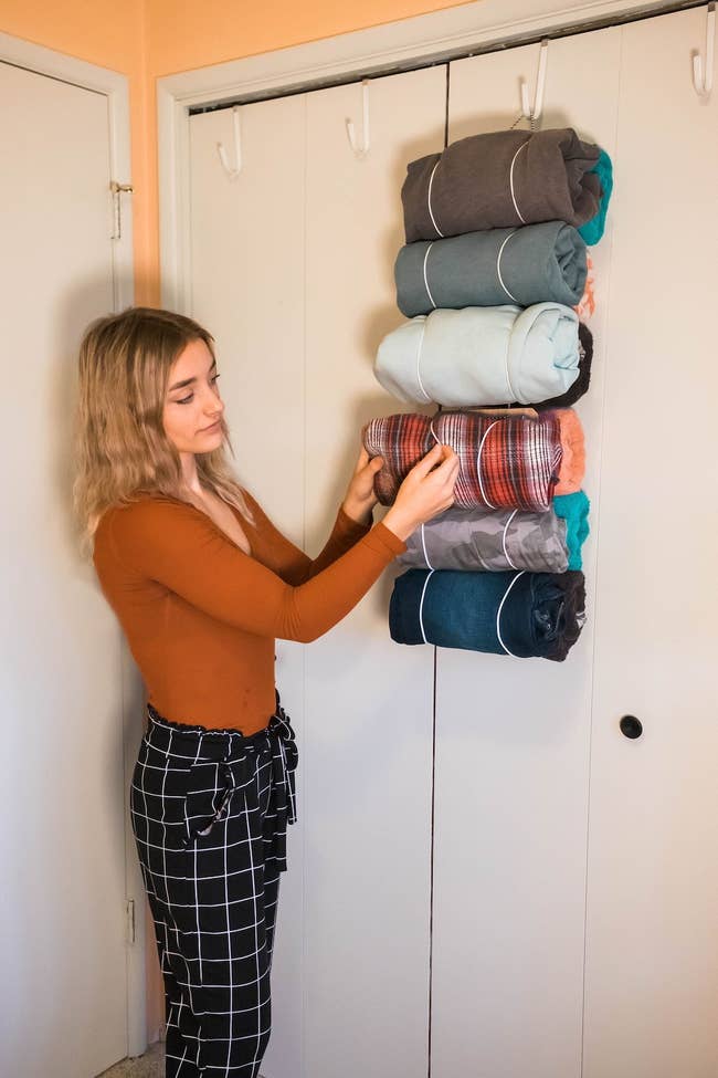 Person stacking neatly folded blankets on a shelf for storage