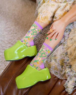 model wearing socks peeking out of green clogs