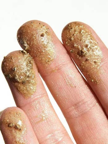 the shimmering coffee scrub on a model's fingers