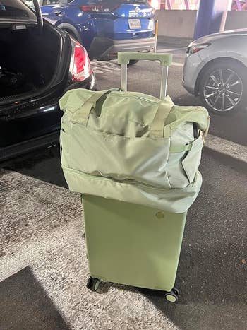 The bag in green on top of a suitcase