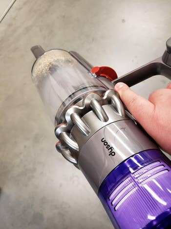 reviewer holding the handheld portion of the Dyson vacuum