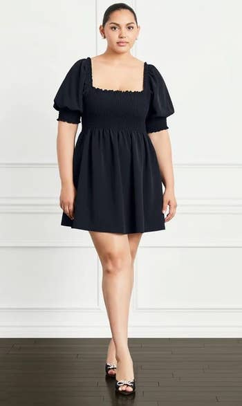 a model wearing a puff-sleeve babydoll dress in black 