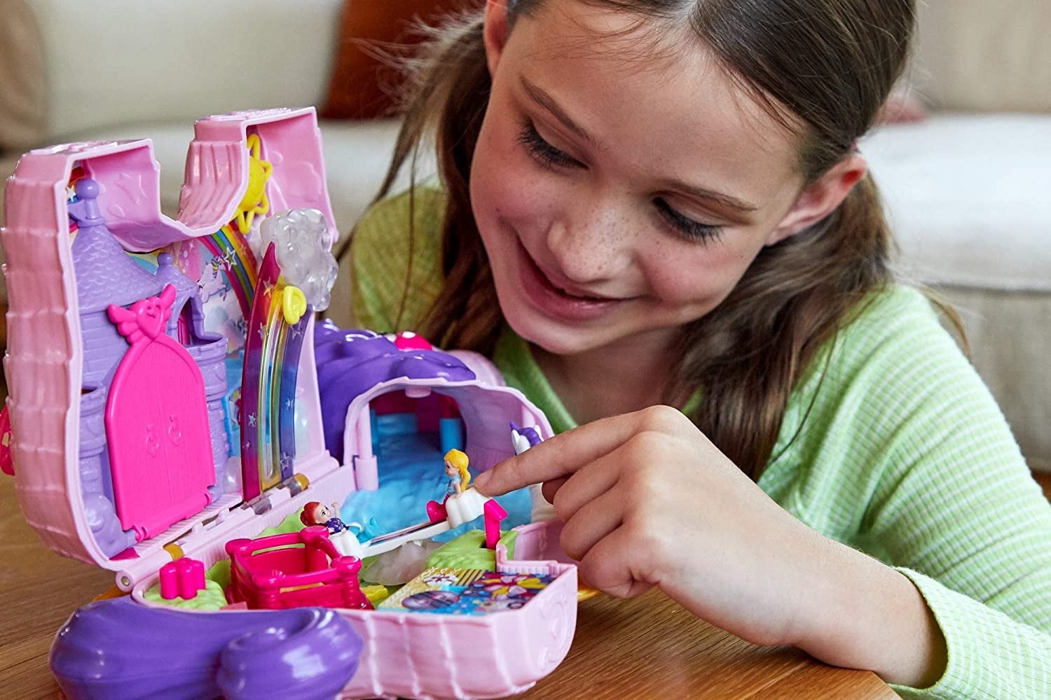 Child model playing with pink and purple plastic unicorn play set