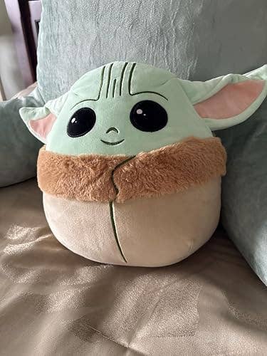 Plush artifact  inspired by a fashionable  sci-fi character, with ample  eyes and fluffy collar, sitting connected  a couch. Ideal for fans and collectors