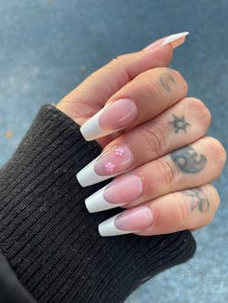 Mid toned reviewer with finger tattoos and the long coffin shaped nails applied